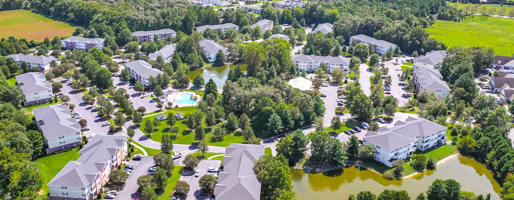 Aerial view of Mill Pond Village apartments showcasing landscaped grounds, residential buildings, and surrounding natural scenery in Salisbury, Maryland